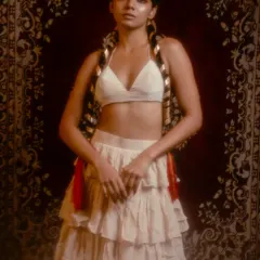 A look from the 'Lila' series, blending bohemian and traditional styles. I paired a tiered skirt and bralette with intricate hair jewelry and long, decorated braids against a rich, tapestry-like backdrop.