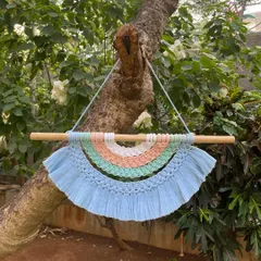 Our rainbow tapestry wall hanging adds a soft, whimsical touch to any room. This piece features pastel shades of blue, green, peach, and white, all handmade with macrame knots.