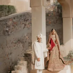 A classic and elegant portrait of the couple on the steps of a palace. Their traditional attire and the historic architecture combine to create a timeless and regal wedding photograph.