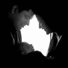 A dramatic and artistic silhouette portrait of new parents adoring their sleeping baby, using light to create a powerful and emotional image.