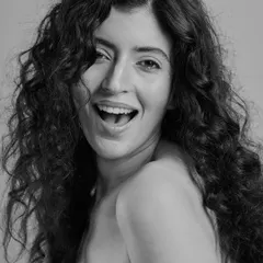 A joyful and candid moment. This black and white shot captures the life and movement of naturally curly hair, paired with a bright, happy expression.