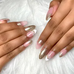 A beautiful set of almond shaped nail extensions with a gold glitter fade. Some nails feature a classic white tip with rhinestone accents, creating a look that is both glamorous and sophisticated.