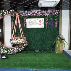 This floral decoration for a naming and cradle ceremony features a beautiful half-moon cradle adorned with flowers against a greenery wall. It's a perfect blend of modern and traditional styles.