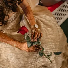 A single red rose held by the bride, her beautifully hennaed hands providing a stunning contrast. A simple, romantic, and elegant shot.