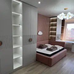 This children's bedroom features a wardrobe with integrated open shelving, illuminated by built-in LED lights. The combination of closed storage and open display space is perfect for organizing clothes, books, and toys.