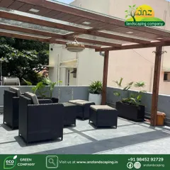 A wooden-finish pergola with a laminated glass roof provides shelter without blocking the sunlight. We furnished this spacious terrace with comfortable wicker seating and planters to create a perfect outdoor living room.