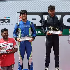 Our driver Rishon Rajeev on the top step of the podium, accepting his winner's trophy. This victory is a direct result of our structured coaching and elite technical support.