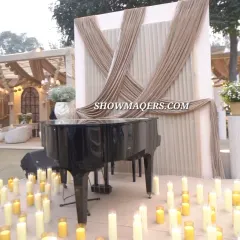 A grand piano set against a draped backdrop and surrounded by candles. This setup provided a focal point for live musical entertainment, adding a touch of classic elegance to the outdoor event.