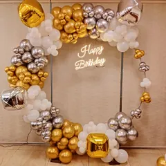 For a modern and chic birthday celebration, I design statement pieces like this circular frame with a custom 'Happy Birthday' neon sign. The organic balloon garland in gold, silver, and white adds a touch of elegance and is perfect for photos.