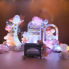 A magical 'love you to the moon and back' theme for a baby's arrival party. The decor features a large crescent moon prop, cloud-like balloon arrangements in pastel shades, and soft, dreamy lighting.