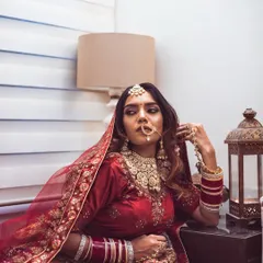 In this shot, the bride's contemplative expression and relaxed posture create a feeling of quiet introspection before the ceremonies begin. The warm lamplight adds to the moody and intimate atmosphere of the portrait.