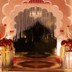 The grand entrance to the wedding, featuring a scalloped arch with hanging crystal strings. This sets a majestic tone, leading guests down a custom-printed carpet to the main event.