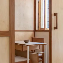 A view through a doorway reveals the minimalist and functional design of the consultation room, with its custom-built desk and chair.
