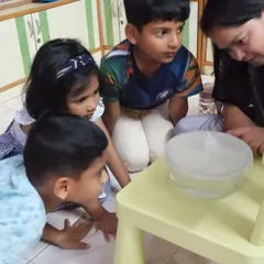 A group of young explorers gathered around to observe condensation forming in our water cycle experiment. Their curiosity and focus are incredible to watch.