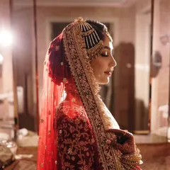 A profile shot of the bride in a quiet moment of reflection. The dramatic lighting emphasizes the intricate details of her veil, jewelry, and the serene expression on her face.