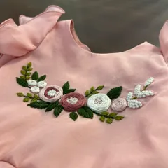 Delicate flower blossoms hand-embroidered with thread, brightening up a lovely pink top for a little one.