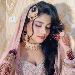 A soft and romantic look for a Nikah ceremony. The makeup features pink shimmery eyeshadow and a matching lip colour, complementing the delicate pink outfit and henna.