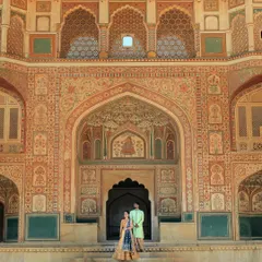 A couple stands before the intricate, ornate facade of a palace in Rajasthan, showcasing a royal theme for their pre-wedding shoot. We excel at using architectural grandeur as a backdrop for couple portraits.