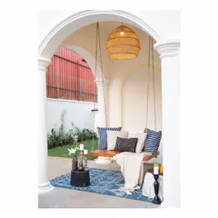 A cozy swing is nestled under an archway in this Goa villa, creating the perfect spot to relax. We believe in creating these intimate corners in our holiday homes, using elements like a wooden swing, a patterned rug, and soft cushions to invite moments of quiet contemplation.