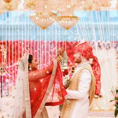 A candid moment from a cross-cultural wedding ceremony, capturing the couple's interaction under a beautifully decorated mandap.