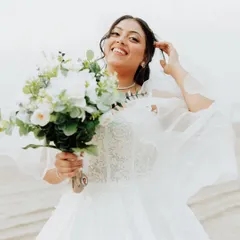 The pure joy of a bride on her wedding day. This candid shot on the beach captures her happiness, with wind-swept hair and natural makeup that looks effortless and beautiful.