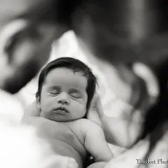 A close-up portrait of a sleeping newborn, framed by the soft focus of their parent's embrace. My newborn sessions prioritize your baby's comfort and safety.