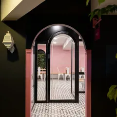 The main entrance to Qoqobae, featuring a custom arched glass door. This architectural element is central to the French cafe concept, creating an elegant and memorable entryway that contrasts with the dark grey facade.