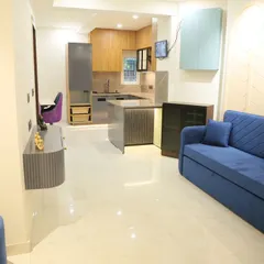 This is a great example of an open-plan living space I designed. The layout connects the living room, dining area, and kitchen, creating a bright and airy feel. The vibrant blue sofa adds a pop of color against the clean, modern finishes.