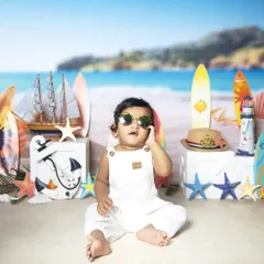 Too cool for the studio beach! This baby is rocking sunglasses in a fun, nautical-themed setup with surfboards and sand.