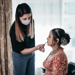 A closer look at the process. Here, I am applying lipstick while the hairstylist works on her intricate floral bun, a perfect example of teamwork.
