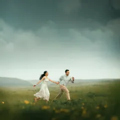 A candid shot of a couple running hand in hand through a vast, open field. This captures the energy, freedom, and pure happiness of being together.