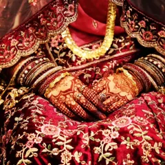 The perfect shot of a bride's hands, showcasing the deep, rich henna stain against her magnificent red bridal lehenga.