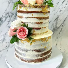 I love the rustic yet chic look of a semi-naked cake. This two-tier version allows the natural cake layers to peek through a light coating of buttercream, decorated with fresh pink and white roses and flecks of edible gold leaf for a touch of elegance.
