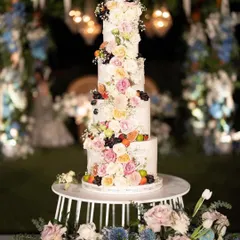 A stunning multi-tiered wedding cake adorned with fresh flowers and fruits, serving as both a dessert and a beautiful decor piece.