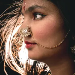 A detailed close-up from a creative shoot, focusing on traditional jewelry and expressive features. The rim lighting beautifully highlights the hair, adding a sense of motion and drama to this profile shot.