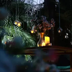 A closer look at the details from the romantic outdoor setup. Hanging glass orbs with candles and a beautiful floral centerpiece add to the enchanting, fairyland feel of the evening.