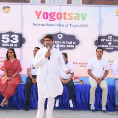 Addressing the audience during a large-scale yoga event. I focus on making yoga accessible and understandable for everyone, explaining the 'jeevan jeene ki kala' or the art of living, in a clear and engaging manner.