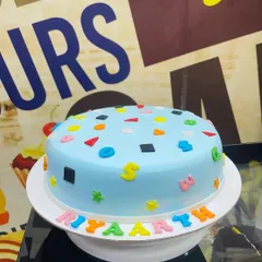 A 1.5kg cake with a simple design featuring colorful letters and shapes.