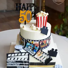 A 50th birthday with a Bollywood bang. This cake is a tribute to classic Indian cinema, complete with an edible film strip, a clapperboard, movie reels, and a bucket of popcorn on top.