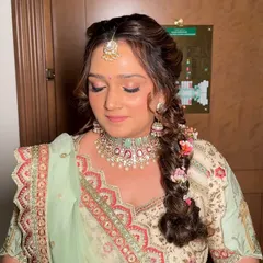 A close-up of the wedding look, featuring shimmery rose-gold eyeshadow and a flawless base. The floral braid adds a beautiful, romantic touch.