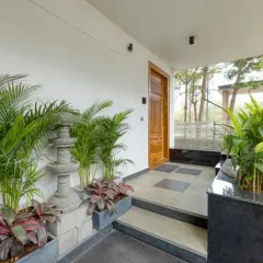 The entrance is designed as a tranquil transition space, with lush planters and a stone pathway leading to the main door.