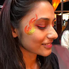 Bringing the heat with this fire-themed face art, complete with a sparkling gold glitter accent. This is a popular choice for music festivals and high-energy events.