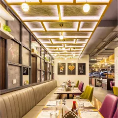 The central bay area at Pasta Street, featuring comfortable channel-tufted booth seating. The custom coffered ceiling with integrated lighting and the curated wall art of Italian elements contribute to the restaurant's authentic theme.
