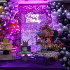 A closer view of the dessert table, highlighting the purple lighting on the sequin wall and the intricate details on the cakes and cupcakes.