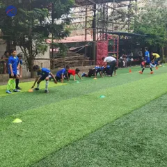 Excellence begins with the fundamentals. Here, one of our expert coaches provides hands-on instruction during a football training drill, focusing on skill development and tactical awareness on an artificial turf pitch.