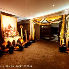 An entrance for a wedding ceremony featuring a Ganesha idol and traditional marigold floral decor. The setup includes long marigold garlands and spotlights to create a warm, inviting, and auspicious welcome.