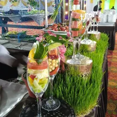 Layered salads served in tall wine glasses, displayed on a bed of wheatgrass for a presentation that is both elegant and natural.