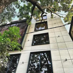 This low-angle view shows the relationship between the building's different materials. The smooth, tiled lower floors contrast with the textured wooden screen above, clearly defining the different functional zones within the mixed-use development.