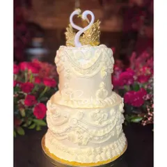 A grand, two-tiered vintage-style cake for a 25th anniversary. The intricate, old-school piping work and the elegant swan topper make it a timeless centerpiece for a milestone celebration.