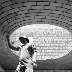 Brick by brick, an earthen shell structure is formed. This image captures a mason at work on the Rohtak Dome, showcasing the raw beauty of the construction phase.